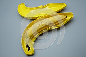 A peeled banana in a yellow plastic container