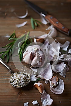 Peeled Garlic Bulb, Rosemary and Salt on a Kitchen Table