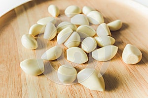Peeled Garlic cloves close up on round wooden plate