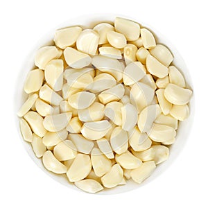 Peeled garlic cloves in white bowl over white