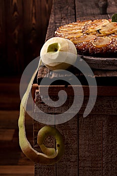 Peeled green apple and french sweet pie tart tatin apple cake upside down and fresh apples  over on old rustic wooden background