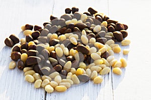 Peeled kernels of cedar nuts in a spoon, two pine cones, green branches