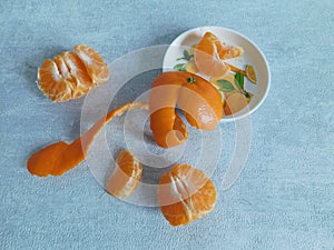 Peeled mandarin without peel and slices of ripe mandarin are on the table