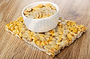 Peeled peanuts in bowl on piece of kozinak on wooden table