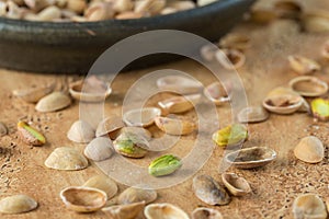 Peeled pistachio grain on the background of scattered shells of nuts on the yellow stone surface. Pistachio texture.