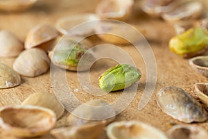 Peeled pistachio grain on the background of scattered shells of nuts on the yellow stone surface. Pistachio texture.