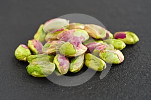 Peeled pistachios on the black stone board