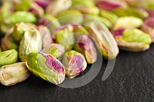 Peeled pistachios on the black stone board