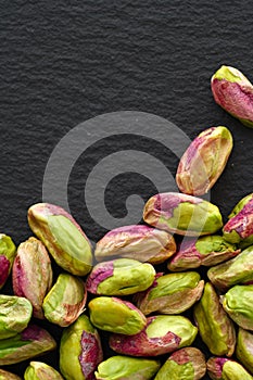 Peeled pistachios on the black stone board, top view