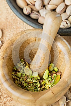Peeled pistachios, crushed into pistachio crumbs in a hand-made wooden mortar. Close-up.