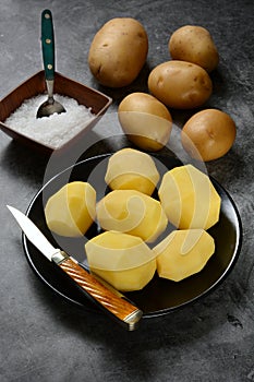 peeled potatoes on black plate - gray background