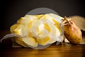 Peeled potatoes closed in a vacuum bag and old sprouted potatoes