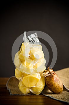 Peeled potatoes closed in a vacuum bag and old sprouted potatoes