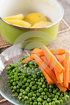 Peeled potatoes with cooked green peas and carrot