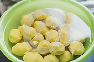 peeled potatoes lie in a green bowl with water. cooking homemade potatoes