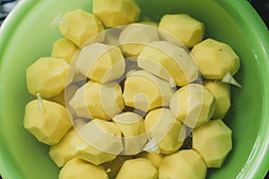 peeled potatoes lie in a green bowl with water. cooking homemade potatoes