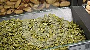 Peeled pumpkin seeds in an open container on a store counter.