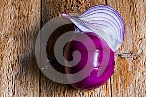 Peeled purple onion cut in half, on weathered wood background