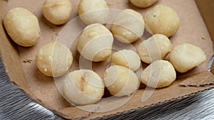 Peeled ready-to-eat macadamia nuts in market paper pack close up