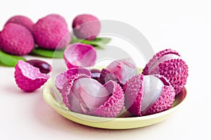 Peeled ripe exotic tropical lychee fruit, in shell, with seeds, green leaves on white background