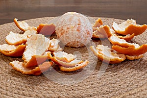 Peeled ripe tangerine in peel close-up on dining table