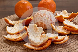 Peeled ripe tangerine in peel close-up on dining table