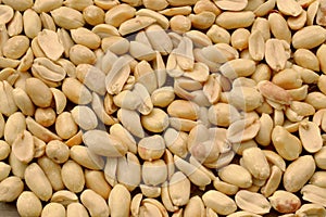 Peeled, roasted peanuts are scattered on the table and make up a background of healthy plant products, the legume family