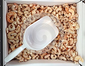 Peeled shrimps with self service food scoop, in the refrigerated container at the fish store