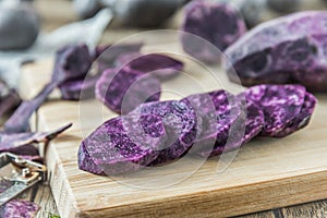 Peeled and sliced purple potatoes on a wooden board