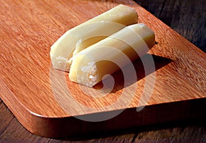 Peeled sugar cane segments stacked together on wooden boards. Chinese fruits