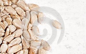 Peeled sunflower seeds on white stone board, closeup view from above, empty space right side