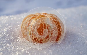 Peeled tangerine close-up on the snow. Christmas or New Year concept