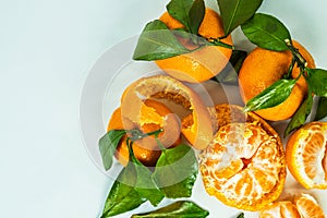 peeled and unpeeled tangerines lie on a white table. Fresh mandarin oranges fruit or tangerines with leaves on a table