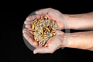 Peeled walnut kernels in male hands on a black background