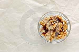 Peeled walnuts in round bowl, close-up, on light background. View from above.