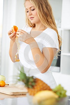 Peeling away the skin to reveal healthy goodness. Curvaceous young woman peeling fruit in her kitchen.