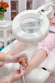 Peeling feet pedicure procedure with eletric device in the beau