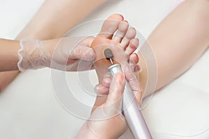 Peeling feet pedicure procedure with eletric device in the beauty salon