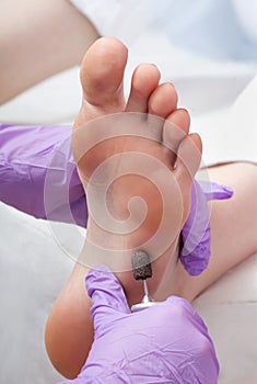 Peeling feet pedicure procedure with eletric device in the beauty salon
