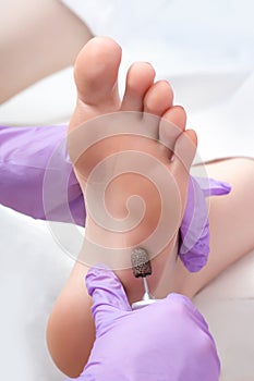 Peeling feet pedicure procedure with eletric device in the beauty salon