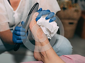 Peeling feet pedicure procedure in salon. Hardened leather grater