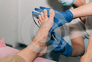 Peeling feet pedicure procedure in salon. Hardened leather grater