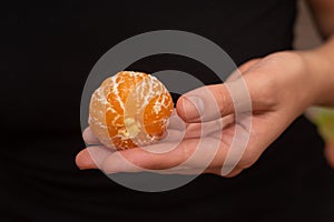 Peeling a Fresh Orange Mandarin. Female Hands skillfully peeling a juicy ripe mandarin