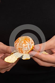 Peeling a Fresh Orange Mandarin. Female Hands skillfully peeling a juicy ripe mandarin