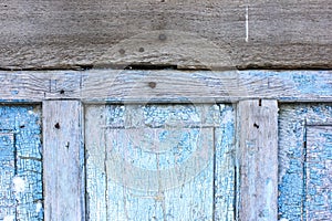 Peeling paint on the old door in the snow. A pattern of rustic blue grunge material. Abstract background.