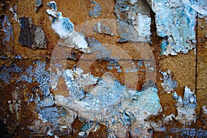 Peeling paint and paper on rusty wall surface