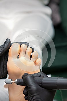 Peeling pedicure procedure on the sole from callus of the female foot by a pedicurist at a beauty salon.