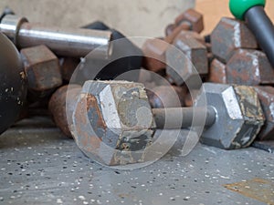 Peeling, rusty dumbbell sitting near stack of other weights in g