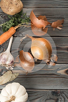 Peeling spicy white onion. Flat lay view. Fresh raw vegetables and flavorings. Rinding onion on kitchen wooden table.