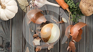 Peeling spicy white onion. Stop motion, flat lay. Fresh raw vegetables. Skinning, rinding on kitchen wooden table.